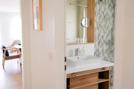 Modernes Badezimmer mit Waschbecken, Spiegel und hübschen Wandfliesen.