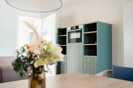 Moderner Küchenschrank mit einem Ofen und einer dekorativen Blumenanordnung.