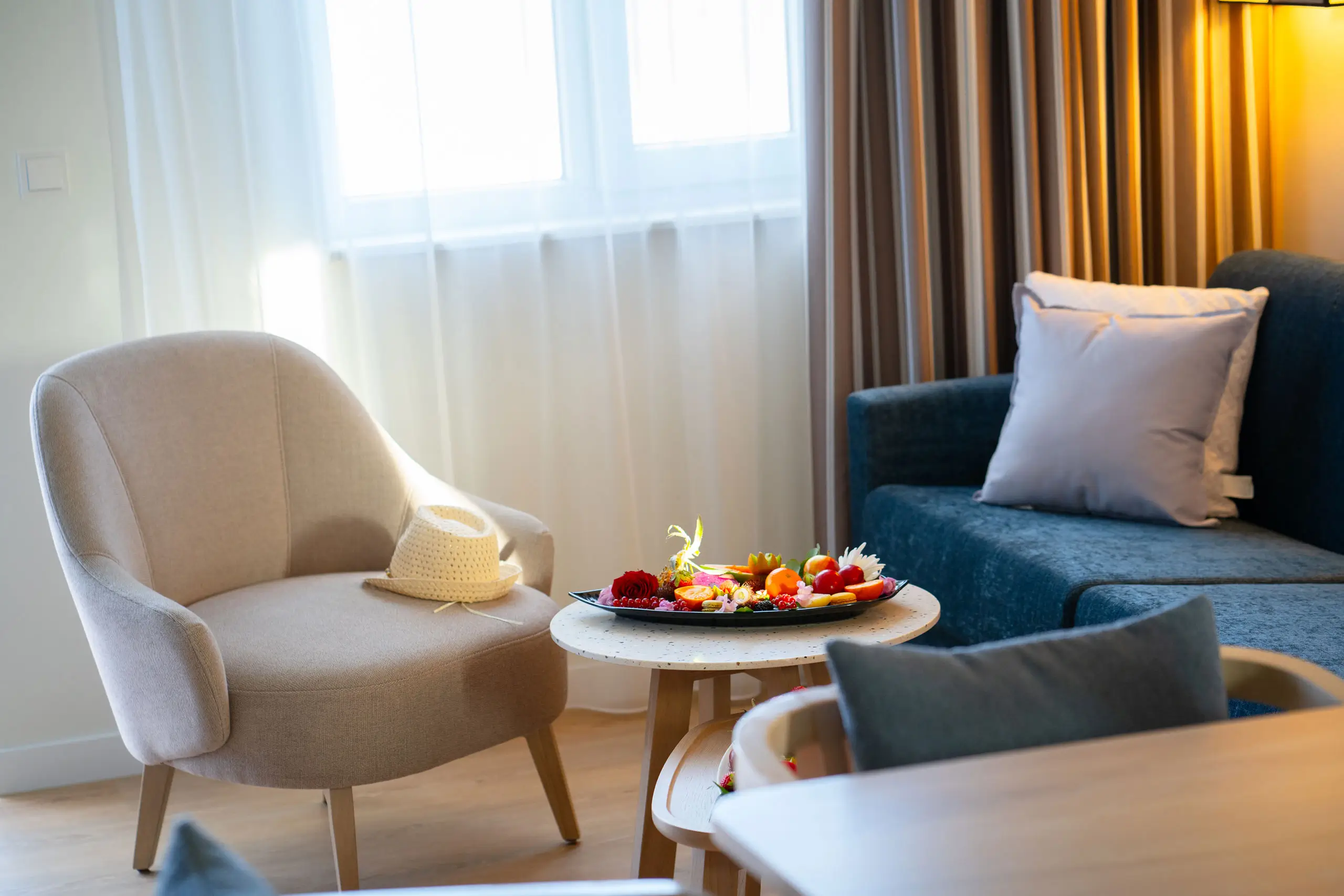 Gemütliche Sitzecke mit einem beigen Stuhl, einer blauen Couch und einem Obstteller.